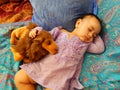Baby sleeps on Asian fabrics with toy