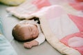 Baby sleeps on bed covered with pink patchwork quilt Royalty Free Stock Photo