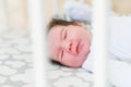 The baby sleeps in the crib. A charming baby sleeps in a crib for sleeping attached to the bed of the parents. A small child Royalty Free Stock Photo