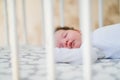 The baby sleeps in the crib. A charming baby sleeps in a crib for sleeping attached to the bed of the parents. A small child Royalty Free Stock Photo