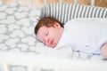 The baby sleeps in the crib. A charming baby sleeps in a crib for sleeping attached to the bed of the parents. A small child Royalty Free Stock Photo