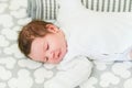 The baby sleeps in the crib. A charming baby sleeps in a crib for sleeping attached to the bed of the parents. A small child Royalty Free Stock Photo