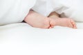 Baby sleeps on a white bed with his feet. Selective focus. Royalty Free Stock Photo