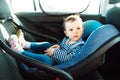 Baby smile in a safety car seat. security. one year old child girl in blue wear sit on auto cradle. Rules for the Safe Transport o Royalty Free Stock Photo