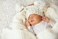 Baby smile in Sleep. Smiling Newborn sleeping on White Blanket in Cradle. Happy Little Child Face in knitted Hat. Cute one month Royalty Free Stock Photo