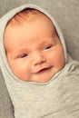 The baby smiles. Newborn 9 days old wrapped in a grey cloth