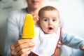 Baby smiling and drooling when trying for the first time an ice cream from his mother`s hands, infant feeding through the baby le Royalty Free Stock Photo