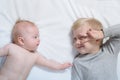 Baby and smiling older brother are lying on the bed. Funny and interact. Top view Royalty Free Stock Photo