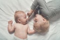 Baby and smiling older brother are lying on the bed. Funny and interact. Top view Royalty Free Stock Photo