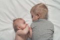 Baby and smiling older brother are lying on the bed. They play, communicate and interact. Top view Royalty Free Stock Photo