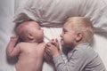 Baby and smiling older brother are lying on the bed. They play, communicate and interact. Top view Royalty Free Stock Photo