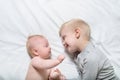 Baby and smiling older brother are lying on the bed. They play, communicate and interact. Top view Royalty Free Stock Photo