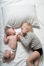 Baby and smiling older brother are lying on the bed. They play, communicate and interact. Top view Royalty Free Stock Photo