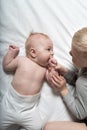 Baby and smiling older brother are lying on the bed. They play, communicate and interact. Top view Royalty Free Stock Photo