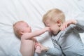 Baby and smiling older brother are lying on the bed. They play, funny and interact. Top view Royalty Free Stock Photo