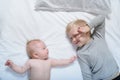 Baby and smiling older brother are lying on the bed. They play, funny and interact. Top view Royalty Free Stock Photo