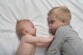 Baby and smiling older brother are lying on the bed. They play, funny and interact. Top view Royalty Free Stock Photo