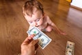 Baby sniffing money, a dollar bill, with weird and funny expression