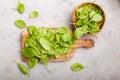 Baby spinach leaves in bowl on grey concrete background, top view, copy space. Clean eating, detox, diet food ingredient Royalty Free Stock Photo