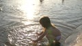 Baby splashing in the water. splashing water. Cute child happily plays on the beach. happy child bathes in the sunset on