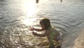 Baby splashing in the water. splashing water. Cute child happily plays on the beach. happy child bathes in the sunset on