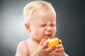 Baby squinting eyes while licking lemon