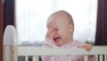 Baby Standing in a Crib at Home. Crying Royalty Free Stock Photo