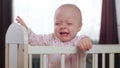 Baby Standing in a Crib at Home. Crying Royalty Free Stock Photo