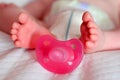 Baby Sucking Pacifier and Feet of a one months old baby wearing diapers lying in bed Royalty Free Stock Photo