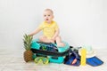 Baby in a suitcase with summer things for vacation, travel and summer concept, copy space