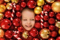 Baby surrounded by lots of Christmas balls and striped candy lollipops