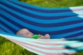 A baby swings in a hammock in the garden on a sunny day Royalty Free Stock Photo