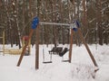 Baby swings in a snow-covered park. A deserted country park with an overcast winter day