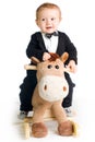 Baby in tailcoat on rocking horse Royalty Free Stock Photo