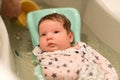 The baby is taking a bath. wrapped in a diaper. Baby having a bath in little bathtub