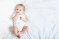 The baby teething Close up portrait of little baby girl in white lying on a white bed Royalty Free Stock Photo