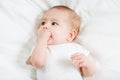 The baby teething Close up portrait of little baby girl in white lying on a white bed Royalty Free Stock Photo