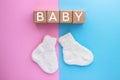 BABY text on wood cubes and pair of cute knitted socks on pink-blue background. Gender of the baby. Boy or girl. Waiting foa a Royalty Free Stock Photo