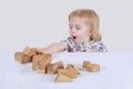 Baby toddler enthusiastically playing with wooden toys in children`s room on a light background concept of happy child, fun game Royalty Free Stock Photo