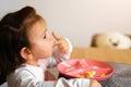 Baby toddler girl eats her lunch on the kitchen with spoon. Messy hands