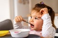 Baby toddler girl eats soup with spoon in her hand. Royalty Free Stock Photo