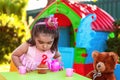 Baby toddler girl in outdoor second birthday party blowing candle on muffin