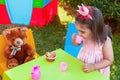 Baby toddler girl playing in outdoor tea party drinking from cup with best friend Teddy Bear Royalty Free Stock Photo