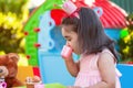 Baby toddler girl playing in outdoor tea party drinking from cup with best friend Teddy Bear Royalty Free Stock Photo