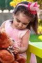 Baby toddler girl, playing in a tea party feeds best friend bff Teddy Bear with candy gummy Royalty Free Stock Photo