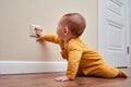 Baby toddler reaches into the electrical outlet on the home wall with his hand. Danger and protection of child fingers from Royalty Free Stock Photo