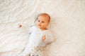 Baby toddler smiles in bed. Top view ovrer little girl lying on white bed