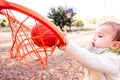 Baby tries to hit a ball in a basketball toy basket