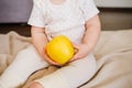 Baby two hands hold yellow apple. Toddler`s hands and fresh fruit front view. Flat lay diet and healthy food concept.