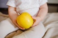 Baby two hands hold yellow apple. Toddler`s hands and fresh fruit front view. Flat lay diet and healthy food concept.